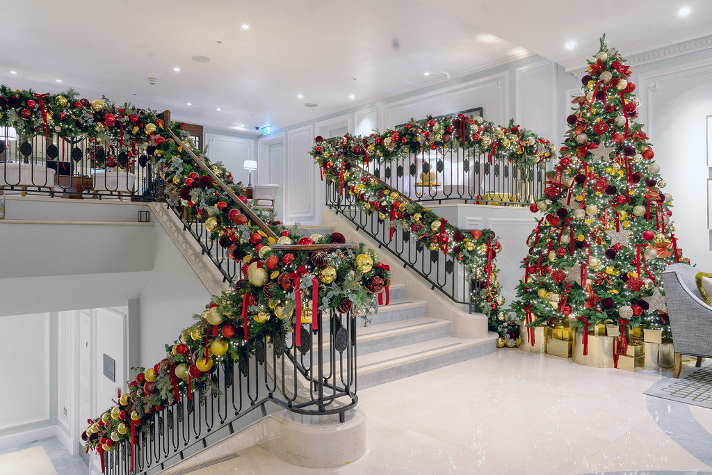 Decorative Christmas tree and garlands on a staircase London installation in a well-lit room.