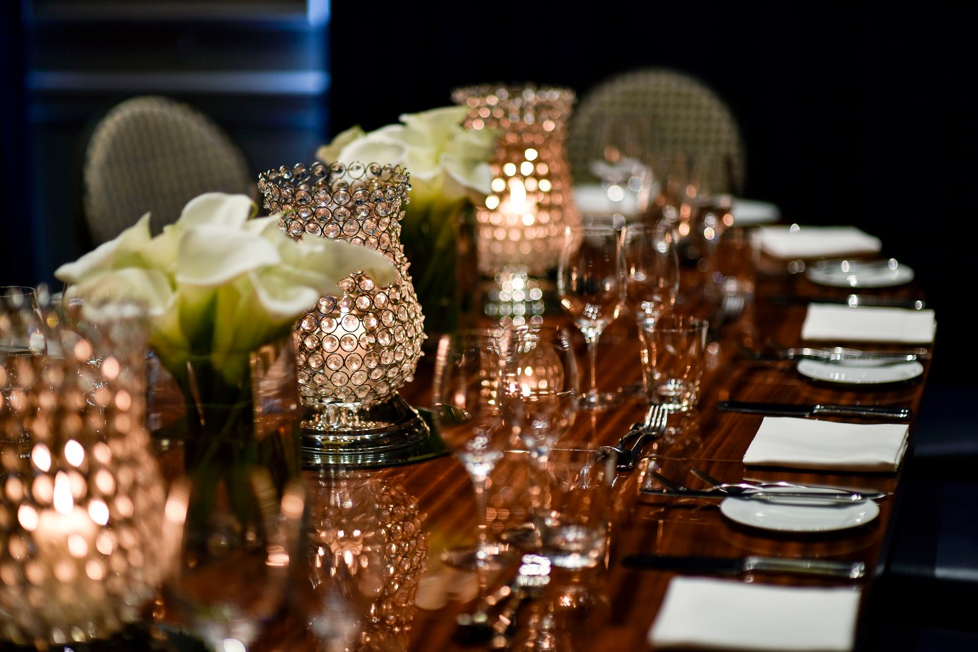 Decorative table setting with candles, flowers, and cutlery on a dark background