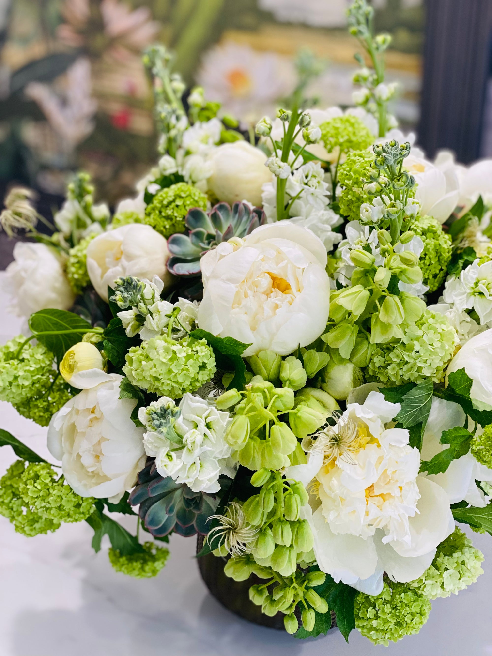 Bouquet of green and white flowers in a vase on a blurred background