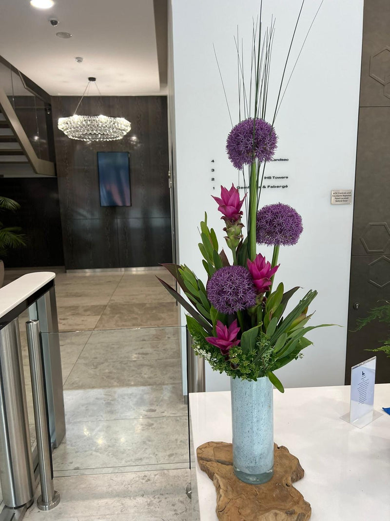 Pink and Purple floral arrangement in a vase on a table with a modern interior background